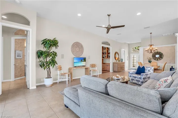 Tiled living room featuring ceiling fan with notable chandelier