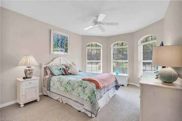 Bedroom featuring ceiling fan, light carpet, and multiple windows