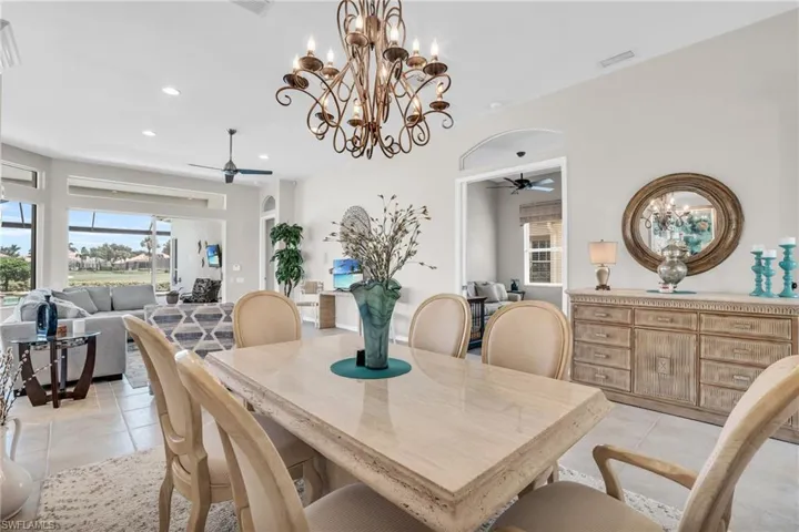 Tiled dining space with ceiling fan with notable chandelier