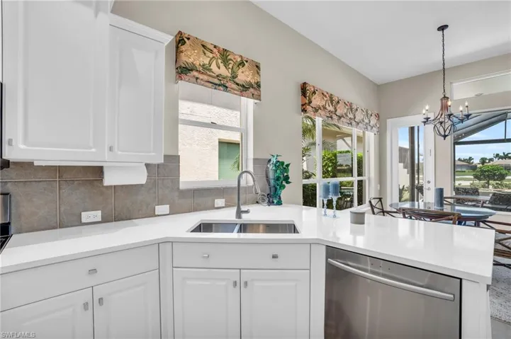 Kitchen featuring stainless steel dishwasher, a chandelier, and white cabinets