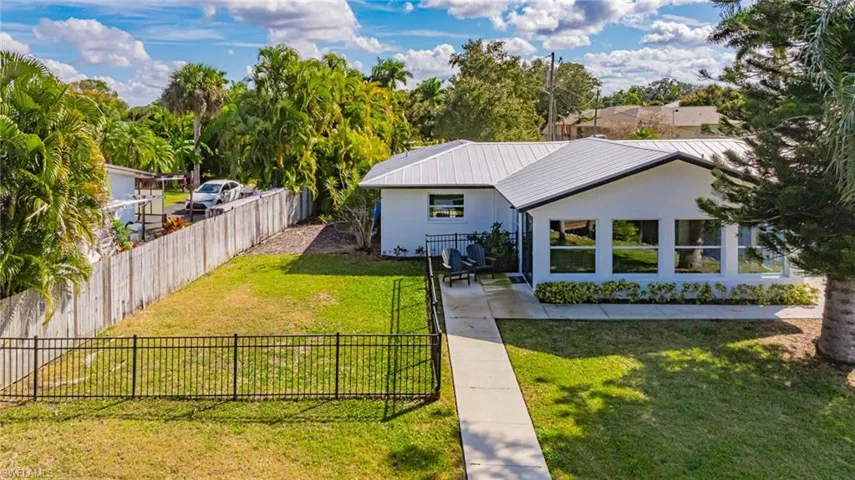 Rear view of house featuring a fenced backyard, stucco siding, and a metal roof