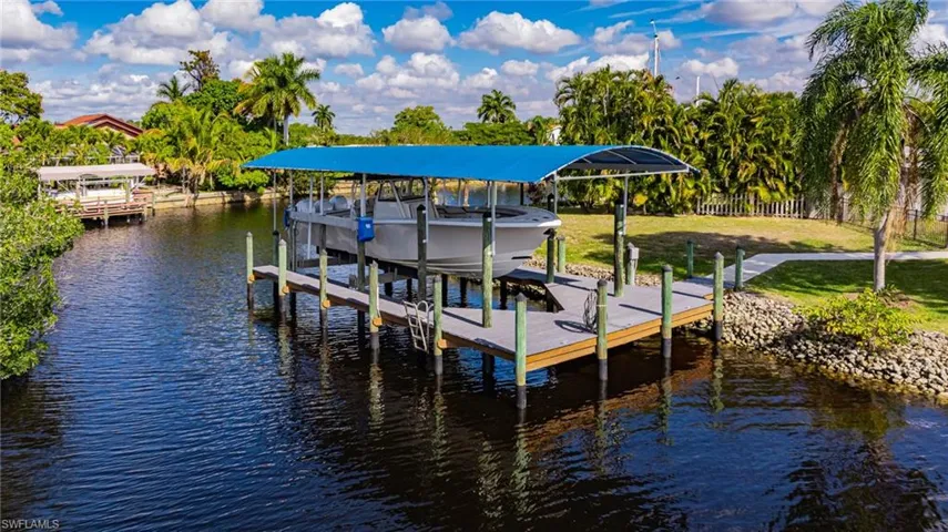 Dock area featuring a water view, boat lift, and a lawn
