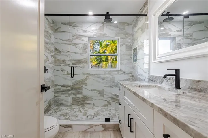 Bathroom with a marble finish shower and vanity