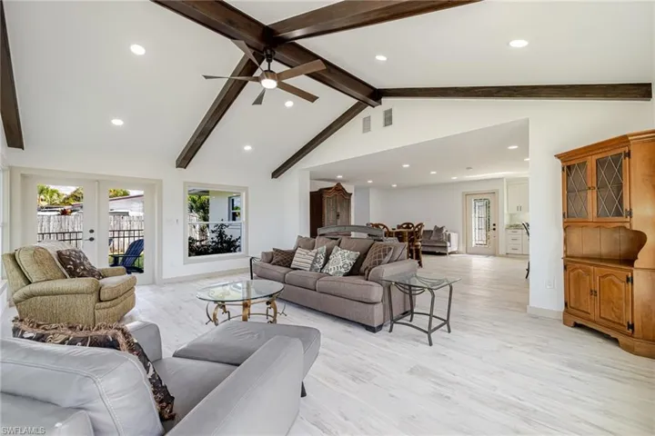 Living room featuring beamed ceiling, recessed lighting, high vaulted ceiling, light wood finished floors, and french doors