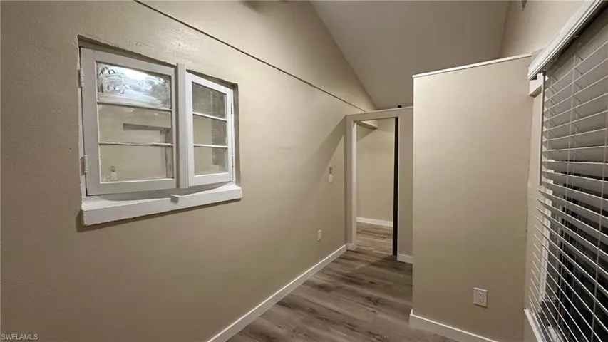 Hallway featuring hardwood / wood-style flooring and vaulted ceiling