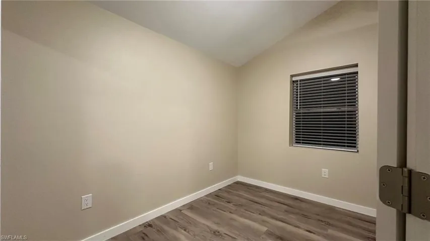 Empty room featuring wood-type flooring and lofted ceiling