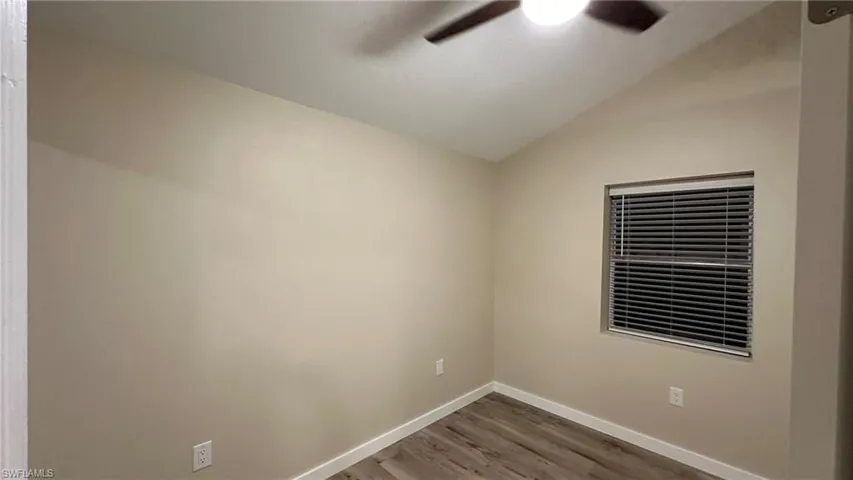 Unfurnished room with hardwood / wood-style flooring, ceiling fan, and vaulted ceiling