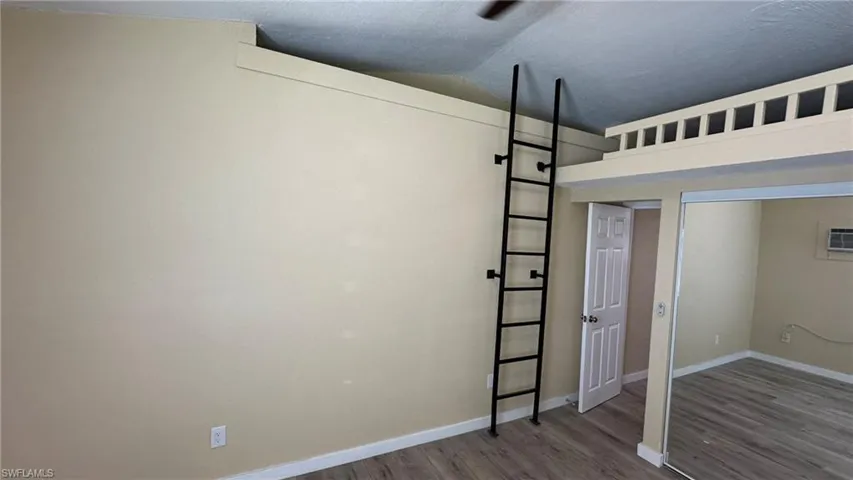 Unfurnished bedroom with wood-type flooring and vaulted ceiling
