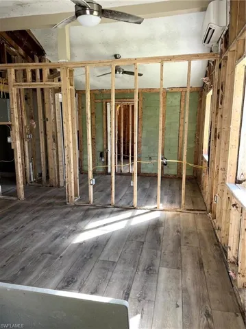 Misc room with hardwood / wood-style floors, ceiling fan, and an AC wall unit