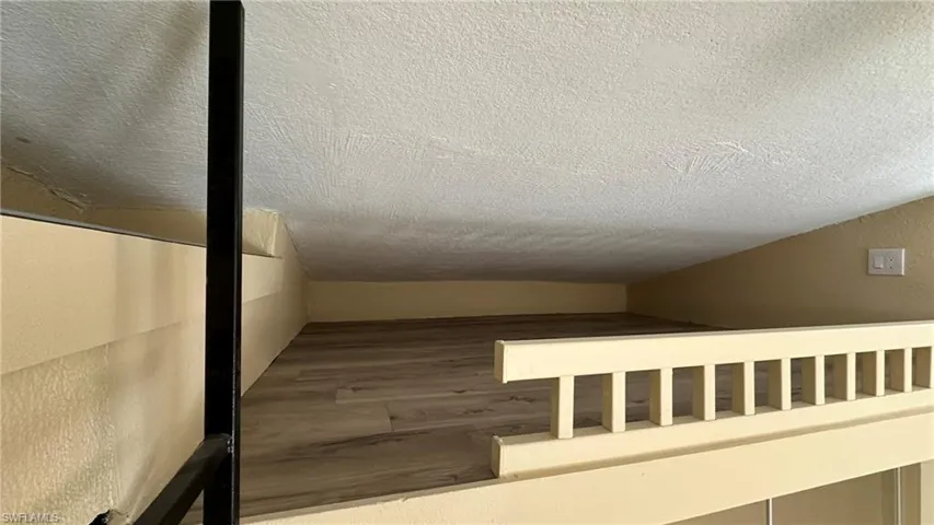 Staircase with a textured ceiling and hardwood / wood-style flooring