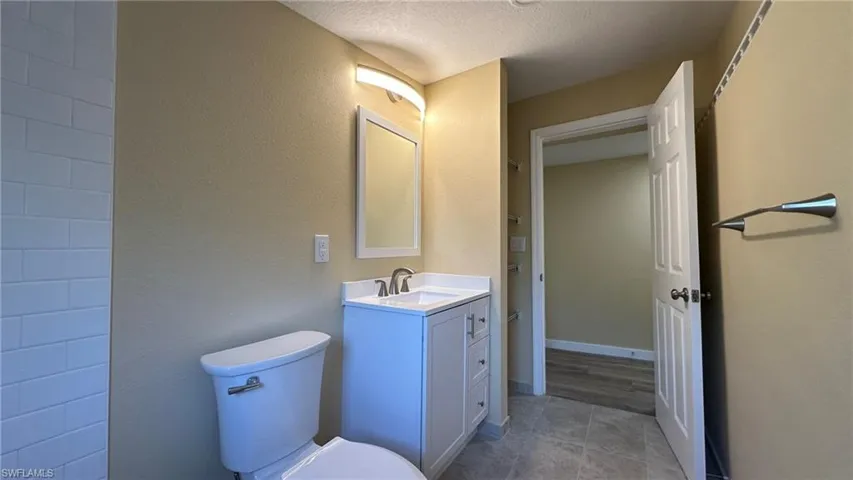 Bathroom with vanity, tile patterned floors, a textured ceiling, and toilet