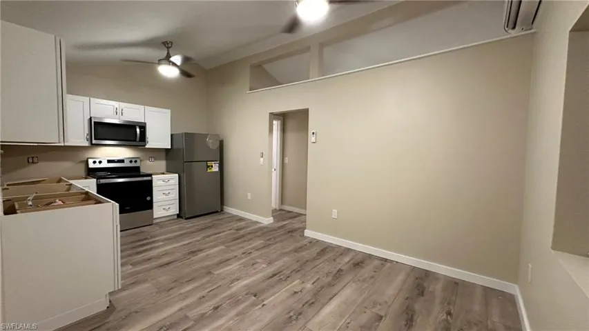 Kitchen with white cabinetry, ceiling fan, lofted ceiling, appliances with stainless steel finishes, and light wood-type flooring