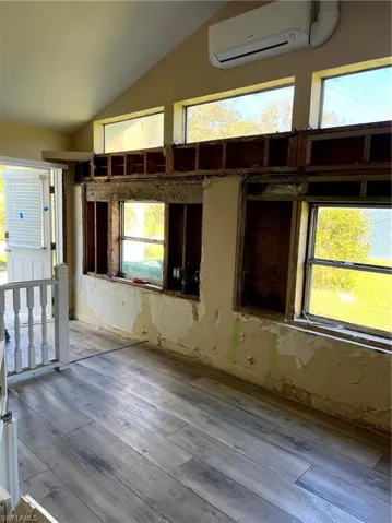 Misc room featuring a wealth of natural light, light hardwood / wood-style floors, lofted ceiling, and a wall unit AC