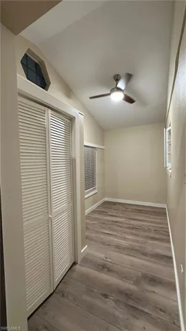 Corridor with lofted ceiling and hardwood / wood-style flooring