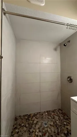 Bathroom with a textured ceiling and tiled shower