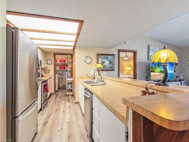 Kitchen featuring stainless steel appliances, sink, white cabinets, and light hardwood / wood-style floors
