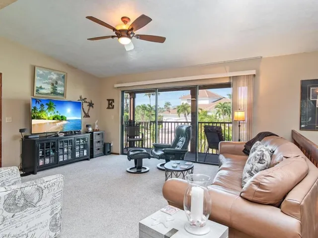 Carpeted living room featuring ceiling fan and vaulted ceiling