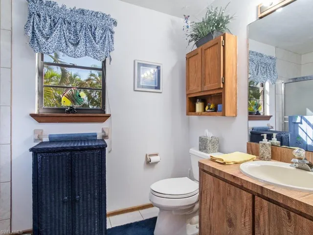 Bathroom with tile patterned flooring, vanity, a shower with door, and toilet