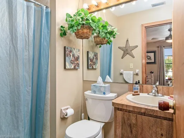 Bathroom featuring ceiling fan, vanity, and toilet