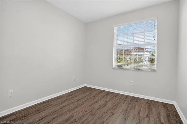 Room featuring light gray walls, wood-finish flooring, and a window with horizontal blinds