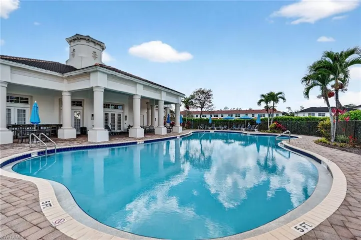 Curved swimming pool bordered by brick-patterned paving