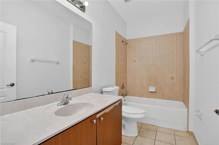 Bathroom featuring a single vanity with integrated sink, wood-finish cabinetry, and a large wall-mounted mirror