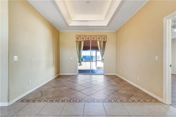 Unfurnished room with a tray ceiling, crown molding, and light tile patterned floors