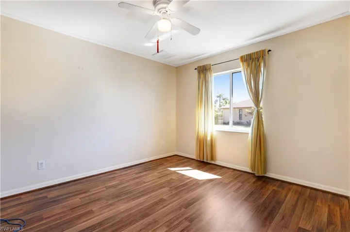 Empty room with ceiling fan, wood finished floors, and ornamental molding