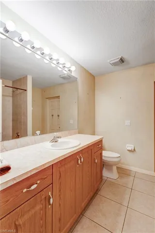 Full bath featuring vanity, a shower, light tile patterned floors, and a textured ceiling