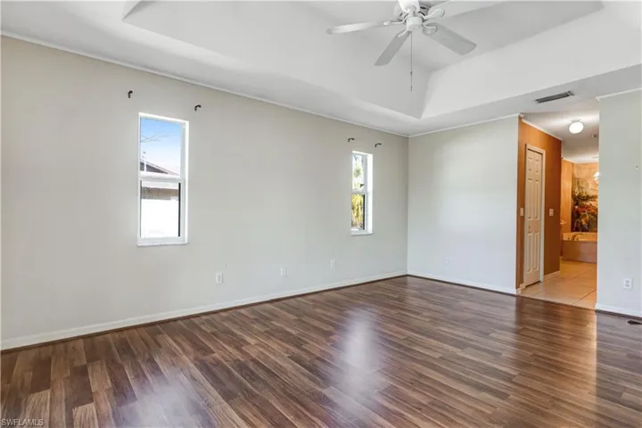Unfurnished room featuring ceiling fan, wood finished floors, and a raised ceiling