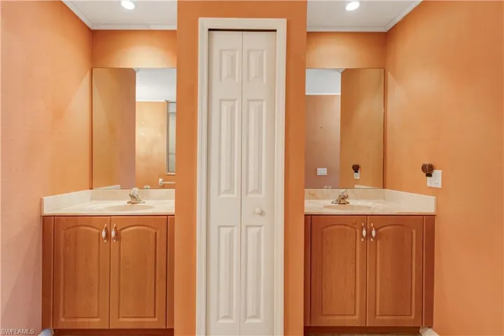 Bathroom featuring a closet, two vanities, and recessed lighting