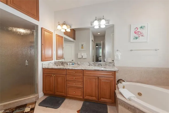 Bathroom featuring a shower stall, a whirlpool tub, double vanity, and light tile patterned flooring