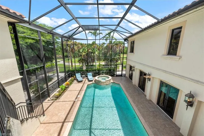 View of pool with a sunroom, a lanai, a pool with connected hot tub, and a patio