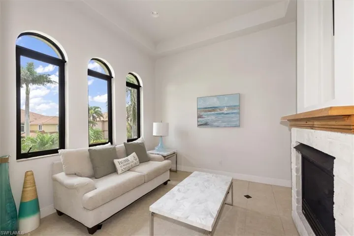 Living room with light tile patterned floors and a stone fireplace