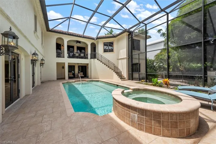 View of pool with a patio area, a pool with connected hot tub, stairway, a sunroom, and glass enclosure