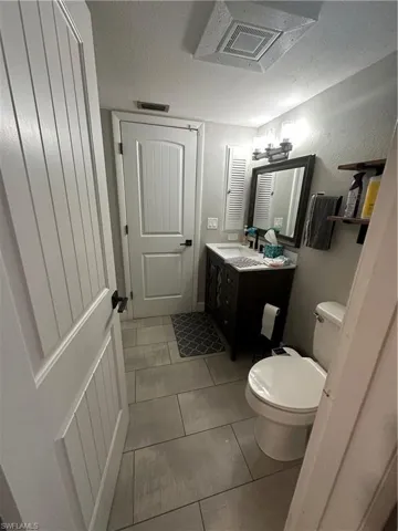 Half bathroom featuring a textured ceiling, cooling unit, vanity, and light tile patterned flooring