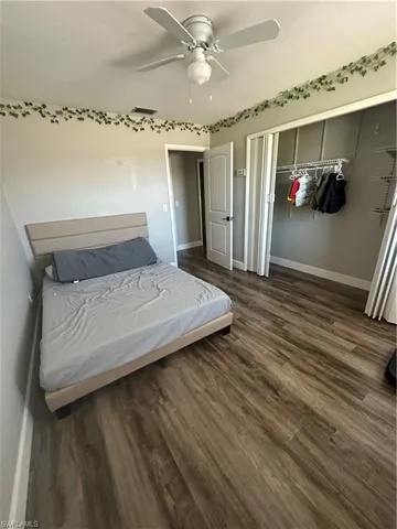 Bedroom with a closet, dark wood-style floors, and ceiling fan