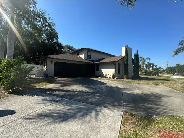 View of side of property with stucco siding, driveway, an attached garage, and a chimney