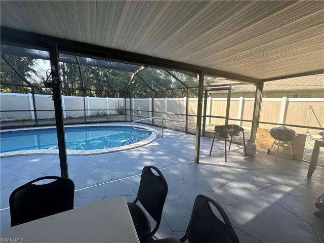 View of pool wih enclosure, area for grilling, and a fenced backyard