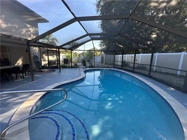 View of pool featuring a lanai, a sunroom, a patio area, a shed, and a fenced backyard