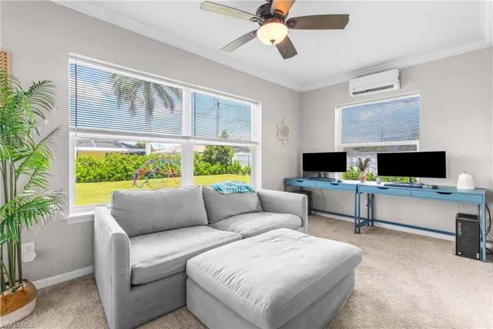 Carpeted home office with ornamental molding, plenty of natural light, an AC wall unit, and a ceiling fan