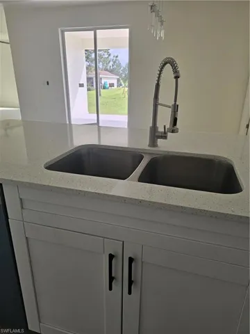 Interior details featuring sink, light stone counters, and white cabinetry