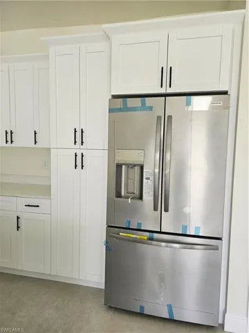 Kitchen featuring white cabinets and stainless steel fridge