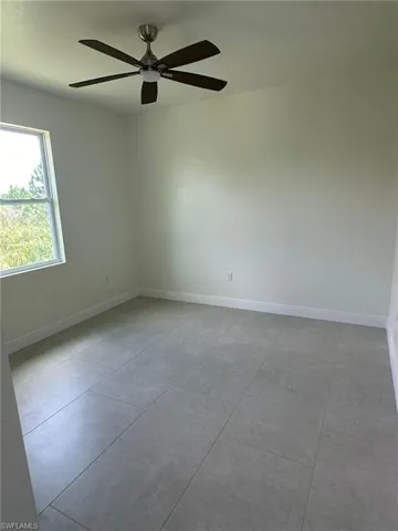 Spare room with ceiling fan and light tile patterned flooring