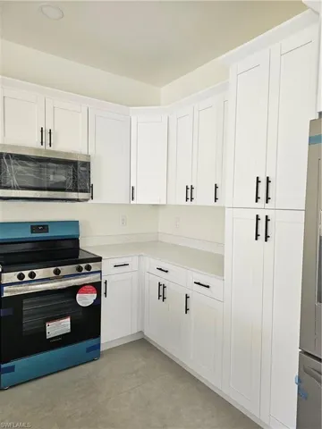 Kitchen featuring stove and white cabinetry