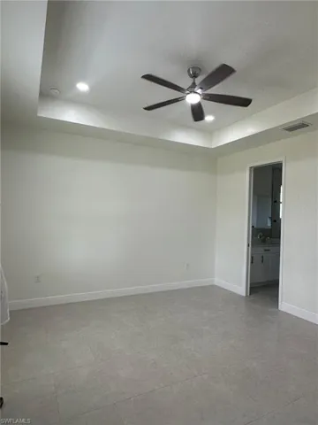 Tiled spare room with ceiling fan and a raised ceiling