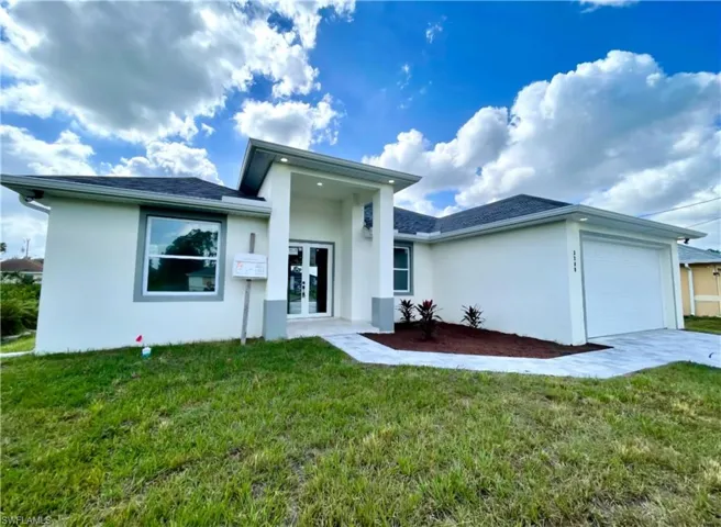 Rear view of property featuring a garage, a lawn, and french doors