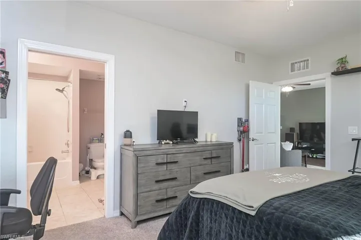 Bedroom featuring light tile patterned flooring, light colored carpet, and an office area
