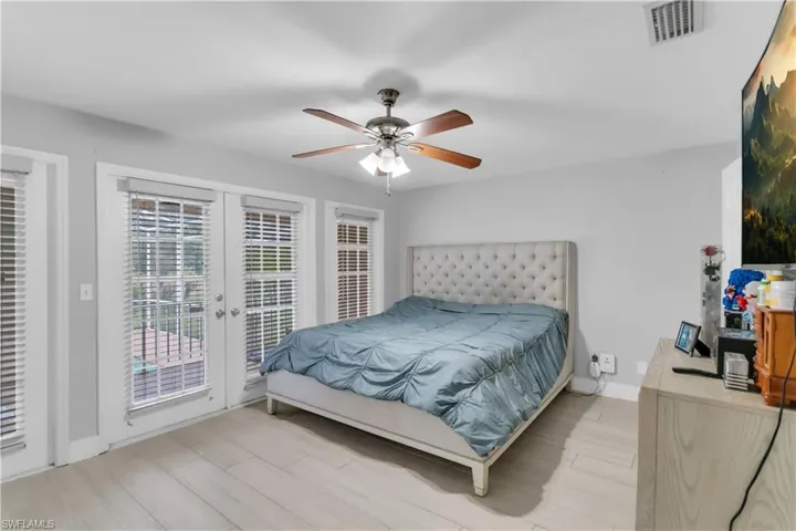 Bedroom featuring access to exterior, light hardwood / wood-style flooring, french doors, and ceiling fan