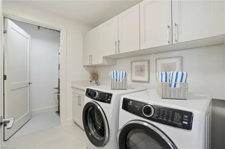 Washroom with washer and dryer, cabinet space, and light tile patterned floors - Virtually Edited Image